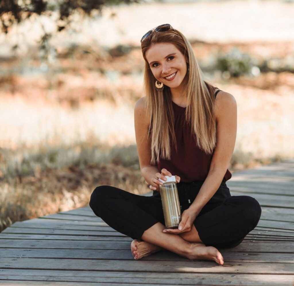 Lea, partner independiente de RINGANA, sentada al aire libre con una botella RINGANA